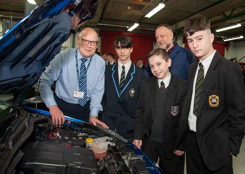 Group of school pupils looking at the engine of a car