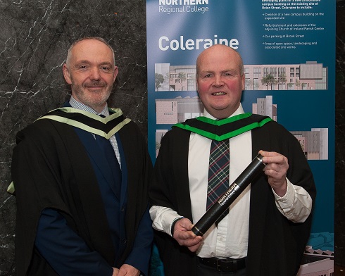Male graduate pictured in robe and scroll with his male lecturer