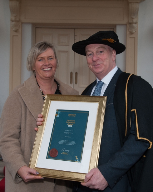 Male honorary fellow pictured with a female holding his framed certificate outside Galgorm Resort and Spa