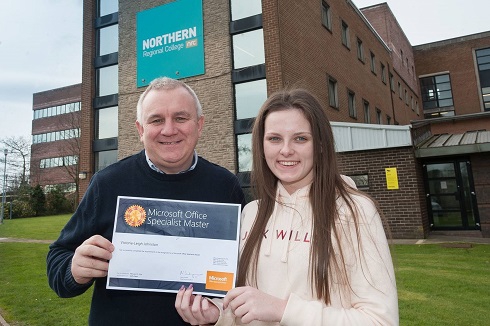 Female student pictured with her MOS certificate alongside lecturer outside Newtownabbey campus