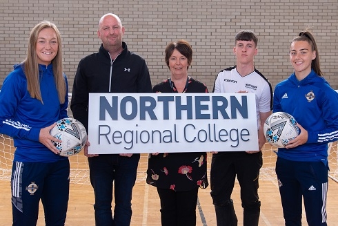 Group holding college logo board and footballs