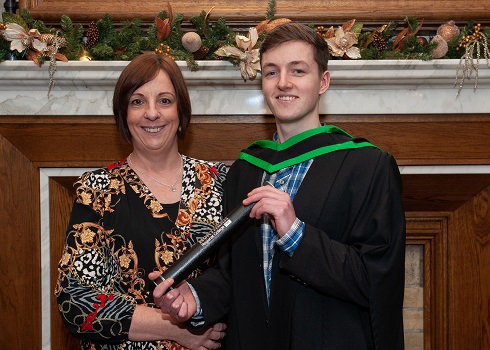 Male sport student in graduation gown with parent