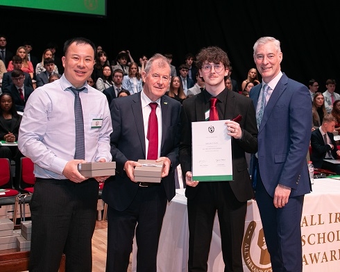 Male student holding a certificate in a group