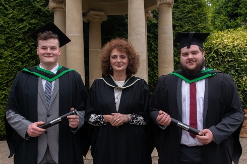 Male students with their femal lecturer in graduation gowns