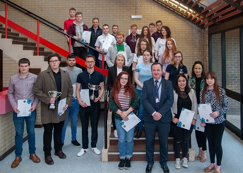 Large group of students holding certificates standing on stairs