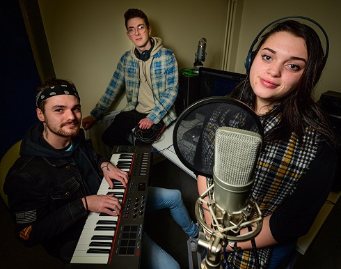 Male media students on a keyboard and female with a microphone