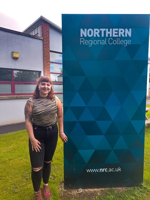 Female standing next to College sign