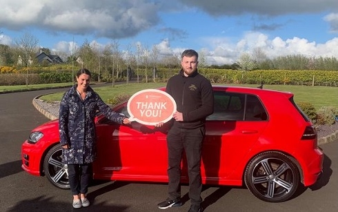 Female and male standing against the red car