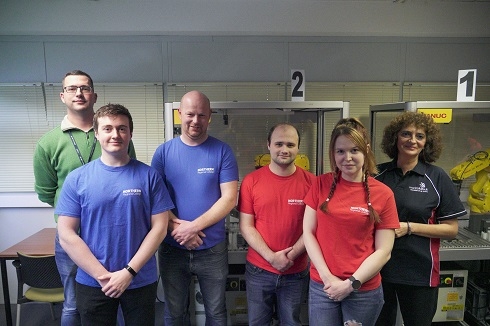 Group standing in front of robotics equipment