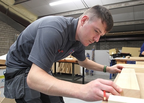 Male apprentice working in joinery workshop