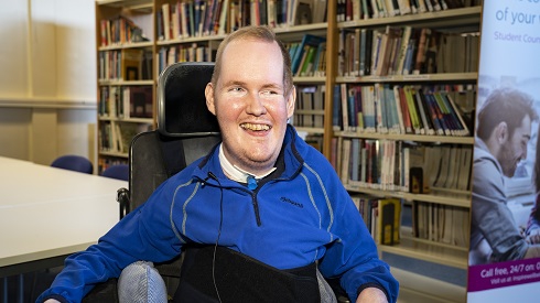 Male student in wheelchair pictured in library