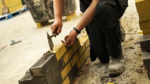 Student laying bricks to construct a wall