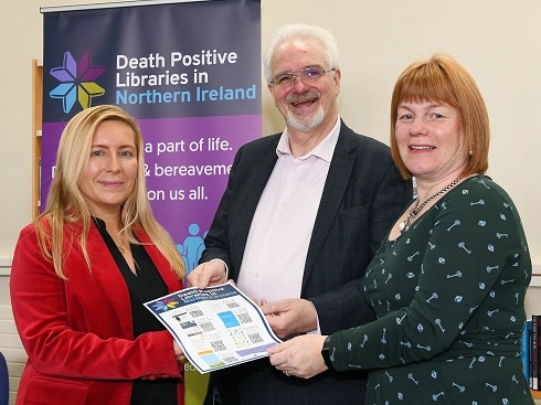 Two females and male holding a flyer