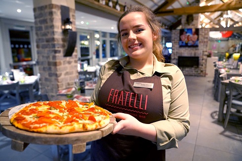 Female apprentice in restaurant holding plate of food