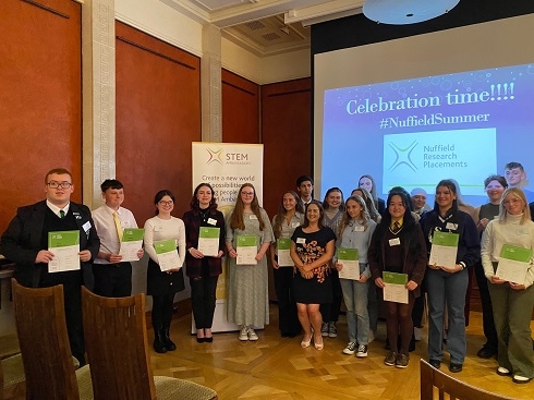 Group of students with certificates standing in front of screen