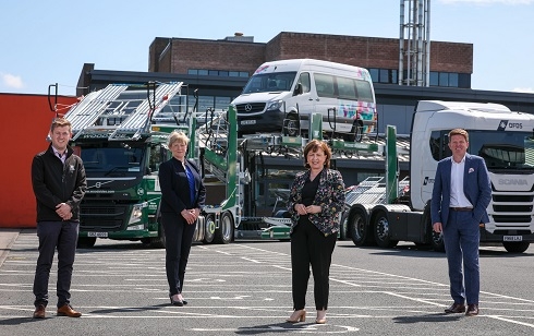 4 people standing outside branded vehicles