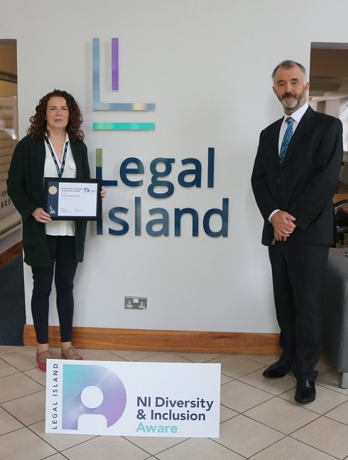 Female Equality Manager pictured with a certificate alongside male representative against Legal Island signage