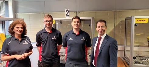 Group of people standing in front of industrial robotics machine