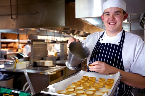 Male apprentice wearing chef whites in the kitchen