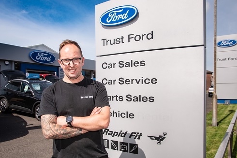 Male standing next to Trustford Signage