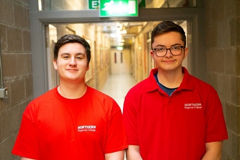 Two males wearing NRC t shirts standing in corridor