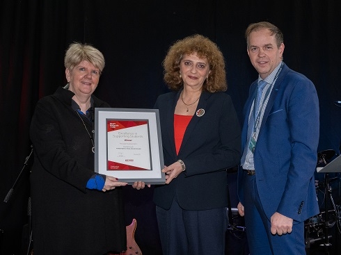 Female lecturer being presented with framed certificate by female and male
