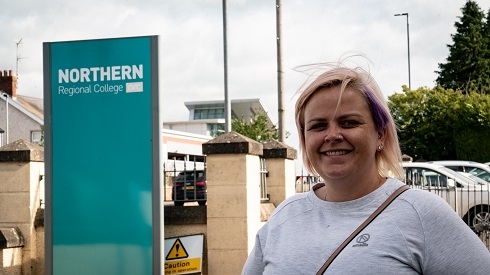 Female standing next to College external signage