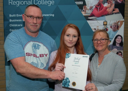 Female student with her parents holding a certificate