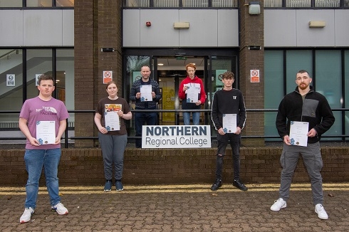 Group of students with certificates outside a building