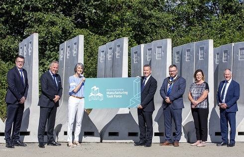 Line up of male and female holding prop with Manufacturing Task Force Logo