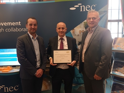 Three males standing together and one male holding an award
