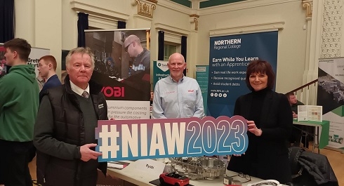 A group holding a prop at an exhibition stand