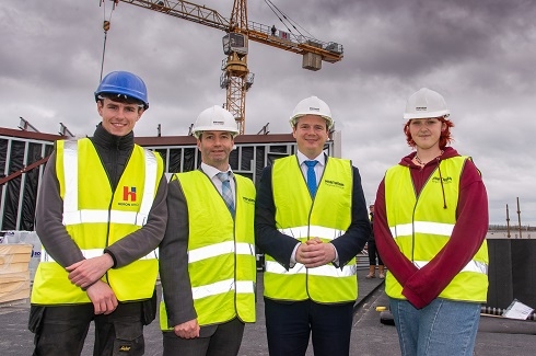 Group in high vis vest standing with crane in background
