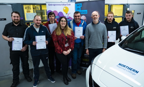 Students with certificates pictured alongside a vehicle