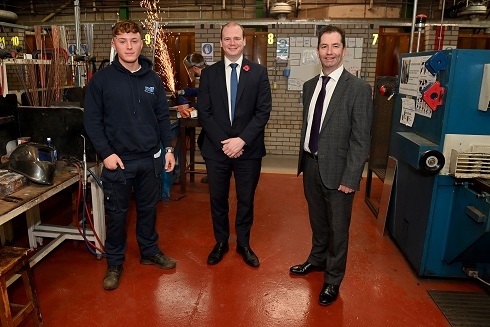 Three males standing in welding workshop