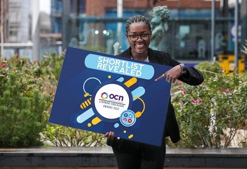 Female holding a prop with text announcing shortlist revealed