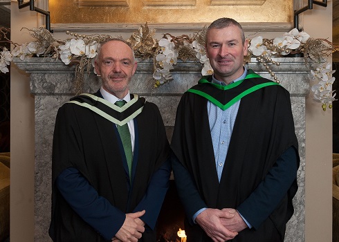 Male student and male staff in graduation gowns