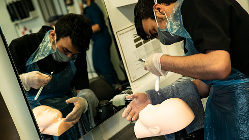 Male student practising shaving on training flat head