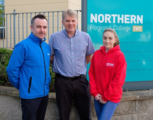 Two males and female student pictured at the College external sign