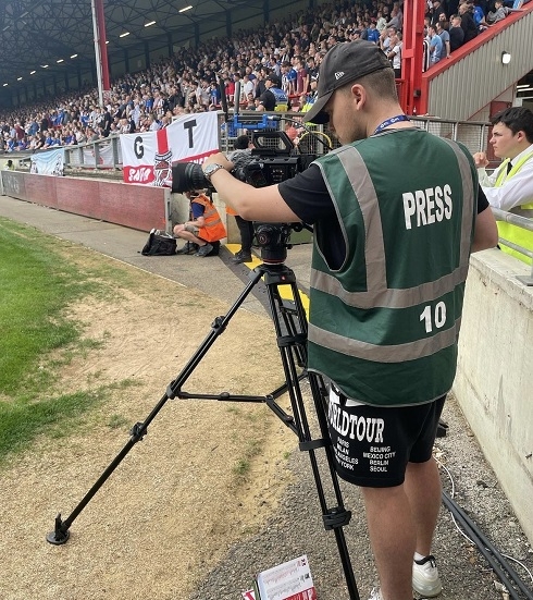 Male behind a camera at a football pitch