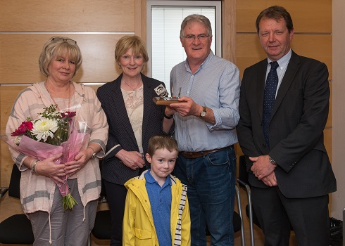 Group photo of male manager receiving his award alongside his family
