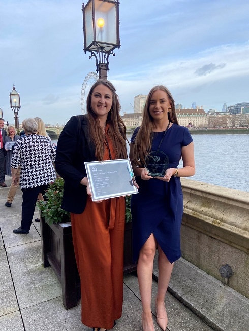 Two females holding awards