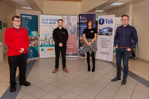 Three males and female standing in front of branded pull up stands
