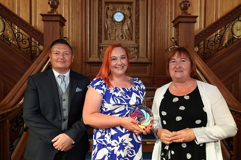 Female award winner with trophy alongside male and female