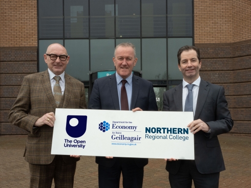 Three males holding a logo board