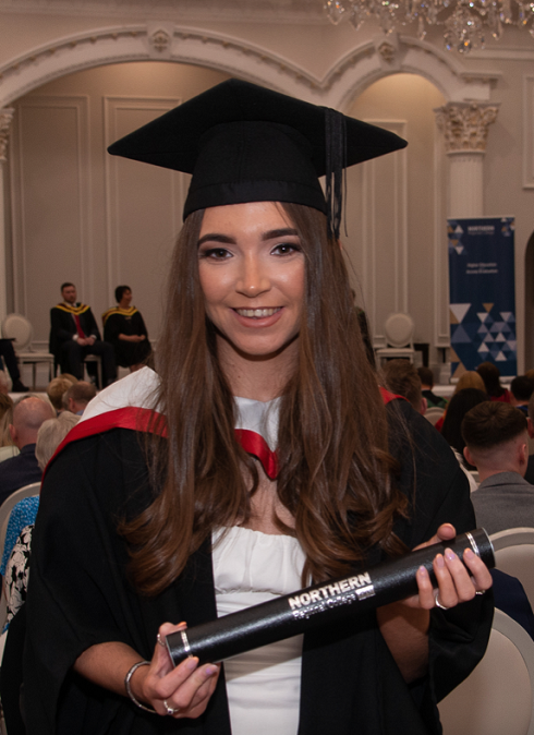 Female in graduation gown holding certificate tube