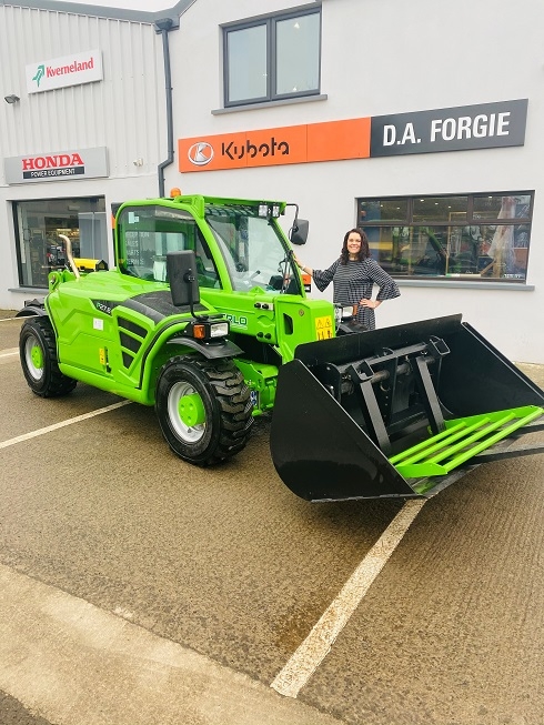 Female standing next to green forklift outside DA Forgie